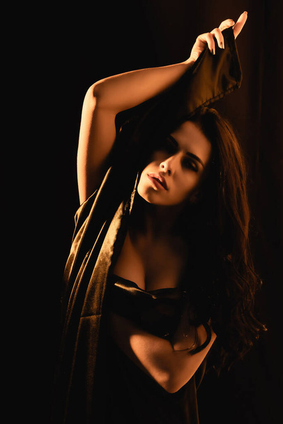lighting on sensual girl covered by silk bed sheet isolated on black  - Fotoğraf, Görsel