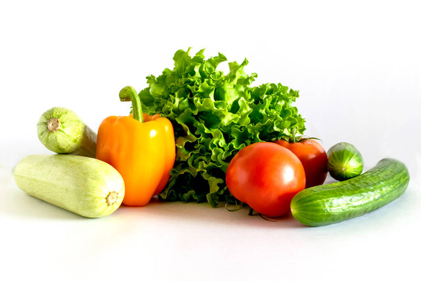 Assortment of healthy food, fresh green red organic vegetables. zucchini, cucumber, lettuce, pepper, tomatoes on a white background. - Foto, afbeelding