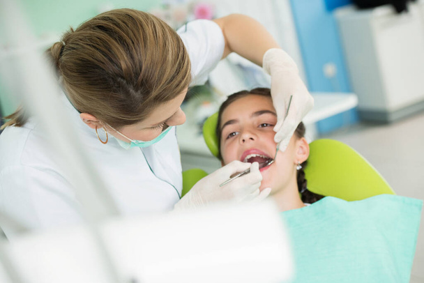 Female dentist and young girl patient in dentist office   - Фото, зображення