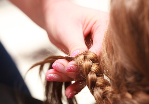 Hairdresser plaiting hair little girl child in hairdressing beauty salon - Fotó, kép