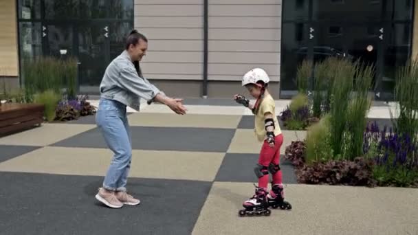 Mom teaches her little daughter to roller-skate. A fun and rewarding pastime. - Felvétel, videó