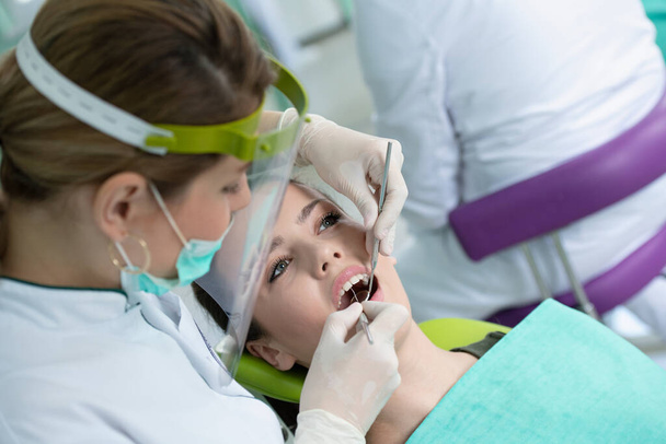 Mulher dentista e jovem paciente em consultório odontológico
   - Foto, Imagem