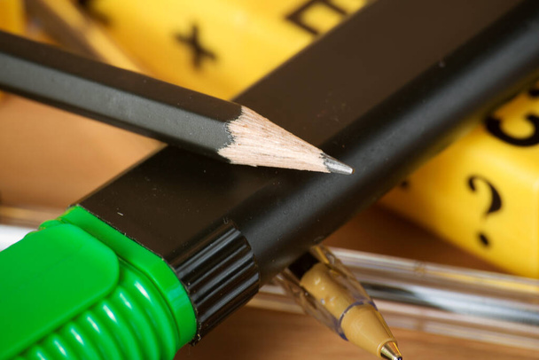 tollak, ceruzák, szövegelválasztók, szalagok, gemkapcsok és egy építőkészlet betűkkel és számokkal egy fából készült asztalon. Iskolaelőkészítő és irodai beszerzések - Fotó, kép