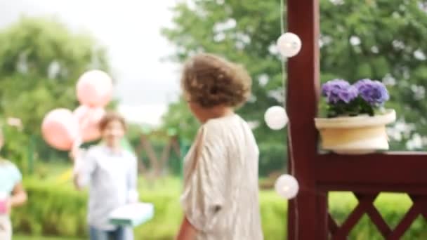 Beautiful curly girl birthday girl accepts congratulations and gifts from her guests. Birthday party, happy childhood, outdoor party - Video