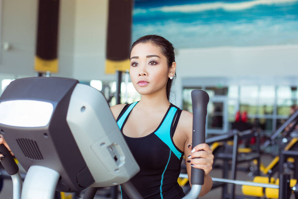 Attractive asian girl at the gym exercising on the xtrainer machine - Fotoğraf, Görsel