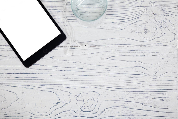 Цифровий планшет, навушники та скляна вода на фоні старого дерев'яного столу
 - Фото, зображення