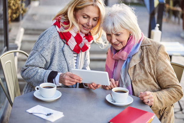 Pretty mature women using tablet in open air cafe - Photo, image