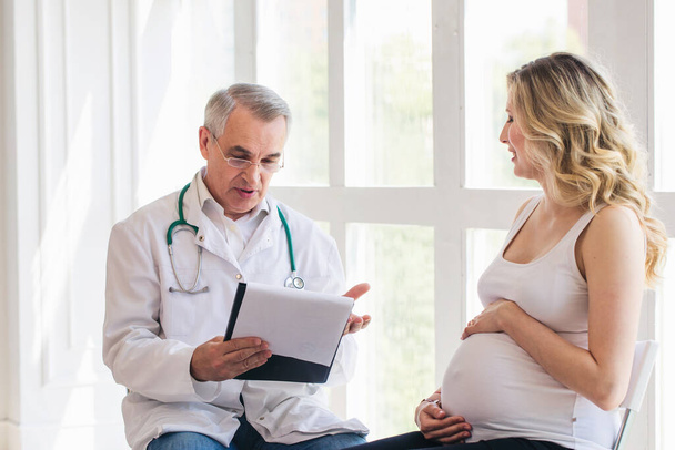 Pregnant woman visiting experienced doctor - Фото, изображение