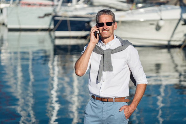 Senior man talking on the smartphone on the marina - Foto, Imagen