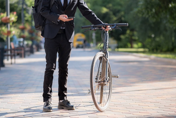 Male person in a suit holding a commuter bike. Cycling around the city, going to work by bicycle - Photo, image