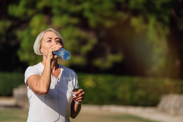 Зріла жінка п'є воду після бігу
 - Фото, зображення