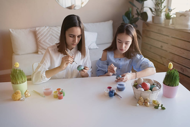                                Happy teini tyttöystäviä maalata munia väreillä ja harjalla kotona. Pääsiäinen, loma ja ihmiset käsite        - Valokuva, kuva