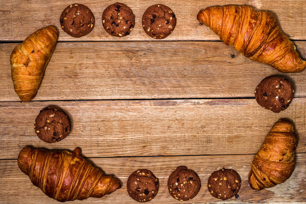 Fresh croissant, puff pastry and biscuits on wooden table. Food and breakfast concept. Desserts and fresh pastries. Top view and copy space - Photo, Image