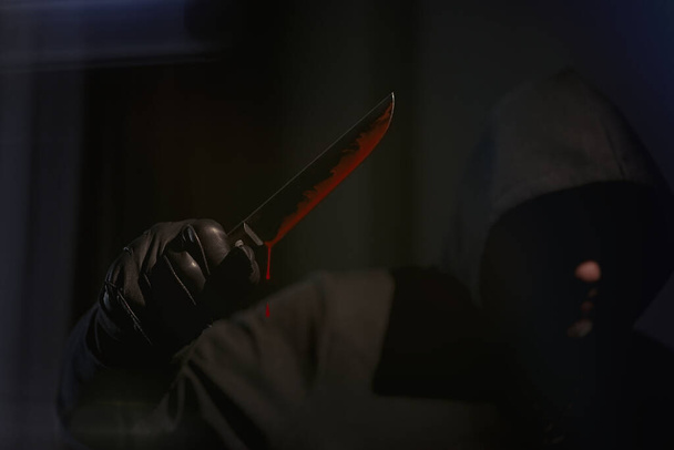                                A man with a bloody knife standing in apartment, hands leather gloves, drop of blood, armed robbery, ruthless assassin            - Photo, image