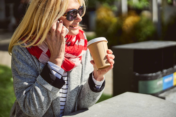 Beautiful happy woman with cup of coffee in the outdoors - 写真・画像
