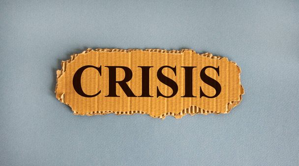 Word 'crisis' on the piece of cardboard on a beautiful white background, copy space. - 写真・画像
