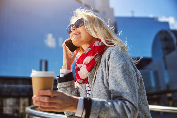 Adult beautiful woman with coffee walking along the street - Photo, Image