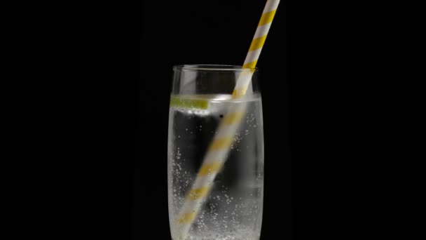 Mixing cold soda water with yellow drinking straw on a black background.  - Footage, Video