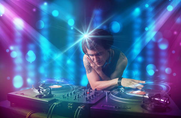 Dj misturando música em um clube com luzes azuis e roxas
 - Foto, Imagem