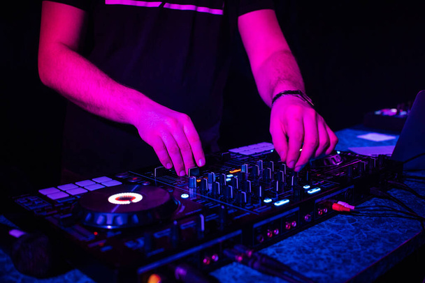 DJは彼の手で音楽コントローラーに電子音楽をミックスします。 - 写真・画像