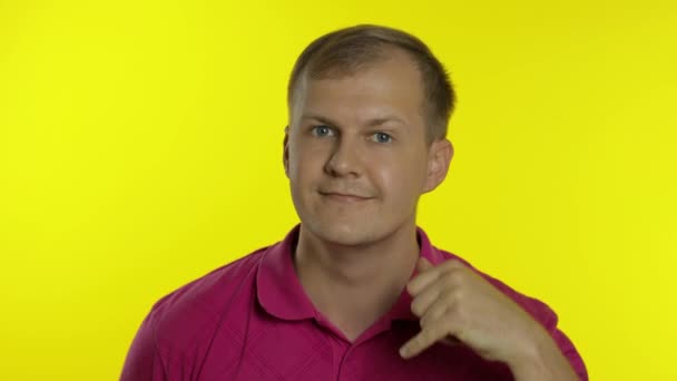 Portrait d'homme posant en t-shirt rose. Un gars heureux qui demande à l'appeler, montre le téléphone avec sa main - Séquence, vidéo