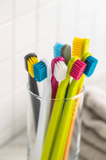 Various colorful toothbrushes in cup. - Φωτογραφία, εικόνα