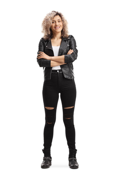 Full length portrait of a young woman in a leather jacket and ripped jeans posing with crossed arms isolated on white background - Fotografie, Obrázek