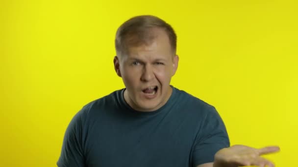 Portrait de jeune homme posant en t-shirt vert. colère insatisfait gars querelles, agite ses mains - Séquence, vidéo
