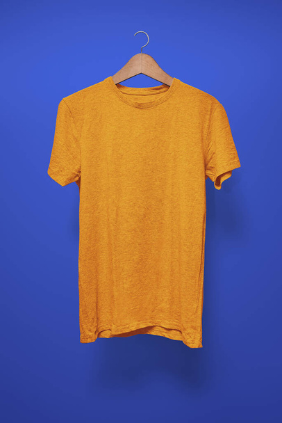 Orange T-Shirt on a hanger against a dark blue background - Photo, Image