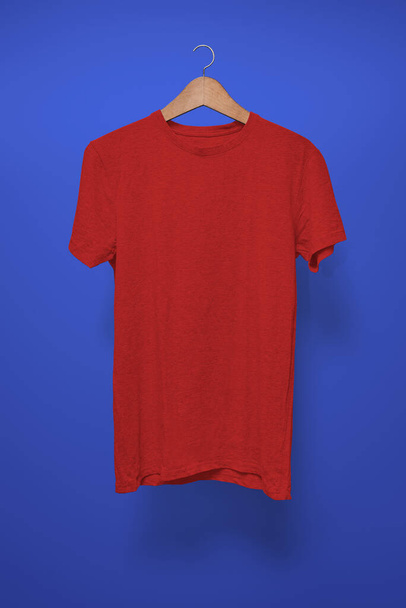 Κόκκινο μπλουζάκι σε κρεμάστρα σε σκούρο μπλε φόντο - Φωτογραφία, εικόνα