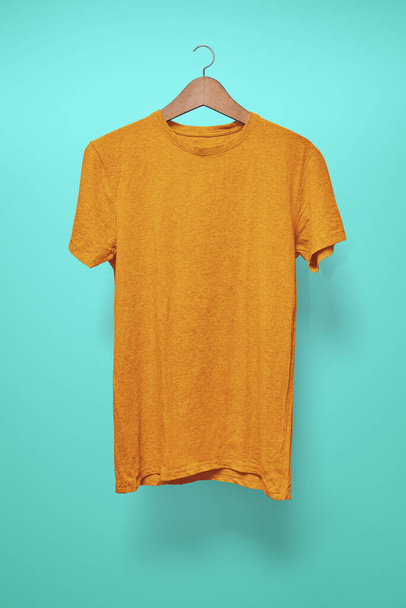 Orange T-Shirt on a hanger against a turquoise background - Fotoğraf, Görsel