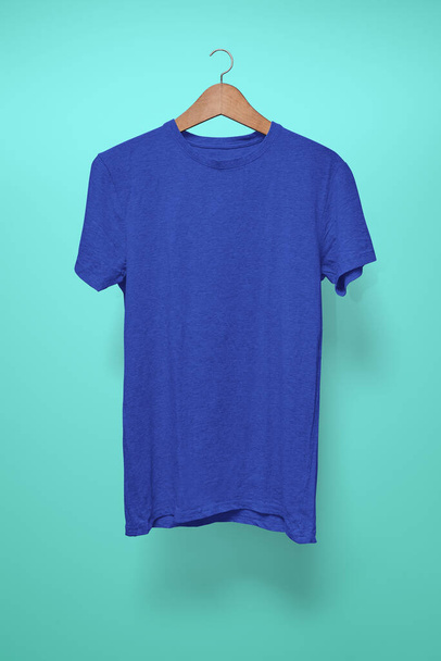 Dark blue T-Shirt on a hanger against a turquoise background - Photo, Image