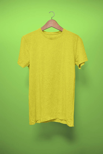 Жовтий T-Shirt на вішалці на зеленому тлі - Фото, зображення