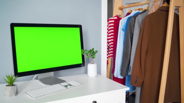 Estúdio criativo - monitor de computador com uma tela verde em primeiro plano. A mulher escolhe roupas ao fundo. Chave Chroma. Espaço de cópia. - Filmagem, Vídeo