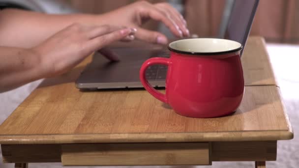 two female hands and a laptop on a wooden bedside table, a girl working at a computer pressing the keys, the concept of remote work at home, freelance - Footage, Video