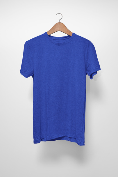 T-Shirt azul escuro em um cabide contra um fundo branco
 - Foto, Imagem