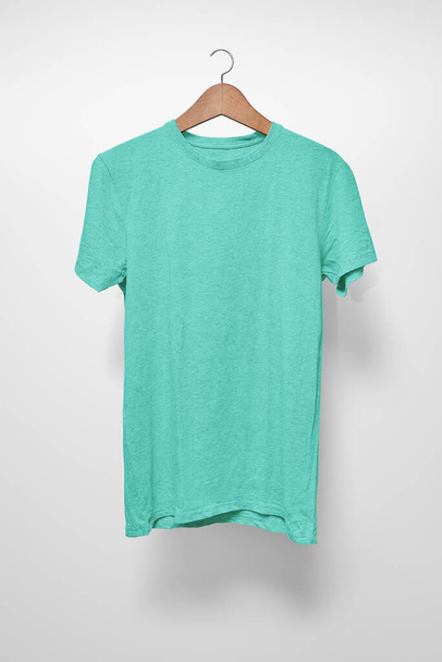 Turquoise T-Shirt op een hanger tegen een witte achtergrond - Foto, afbeelding