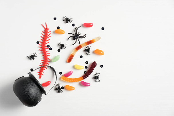 Halloween concept. Creative flat lay composition with pot and halloween candies on white background. - Foto, Bild