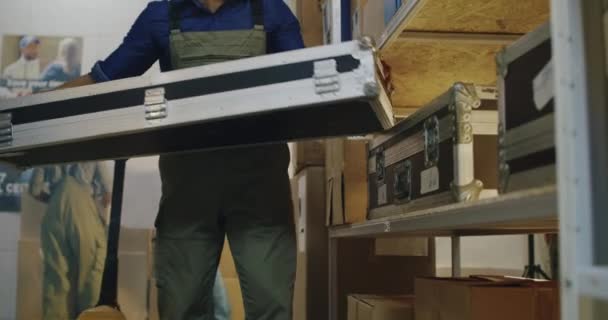 Worker placing road cases on shelves - Video