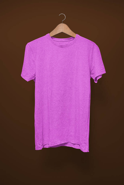 Lila T-Shirt auf Kleiderbügel vor braunem Hintergrund - Foto, Bild