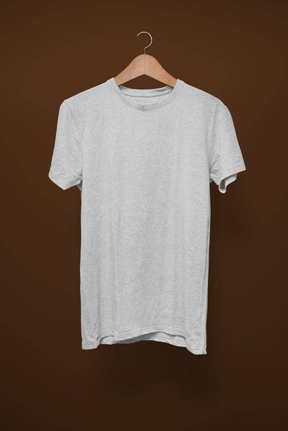 Camiseta gris sobre una percha sobre un fondo marrón
 - Foto, imagen