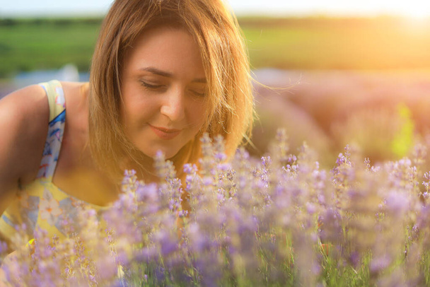 Щаслива молода красива жінка гуляє на заході сонця в лавандовому полі і насолоджується запахом квітів і самотності з природою. Концепція свободи та щастя. Тонований фон
 - Фото, зображення