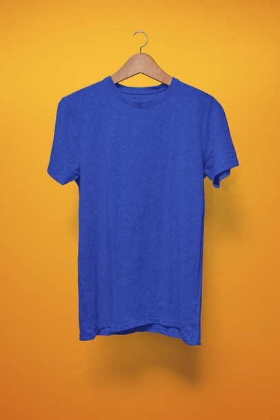 Σκούρο μπλε T-shirt σε μια κρεμάστρα σε πορτοκαλί φόντο - Φωτογραφία, εικόνα