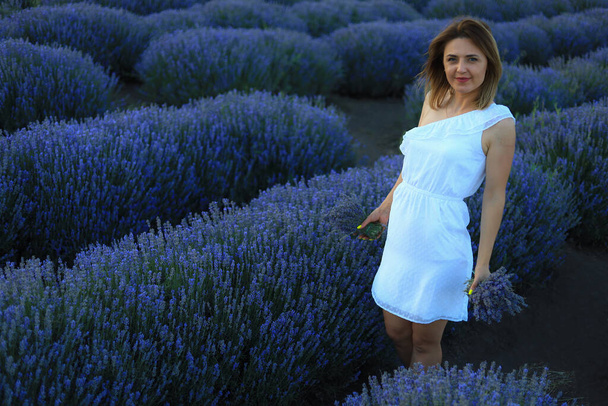 Happy young pretty modest smiling woman enjoying fresh air and aroma at sunset in a lavender field. The concept of freedom and unity with nature. Toned background. Lifestyle emotions - Фото, зображення