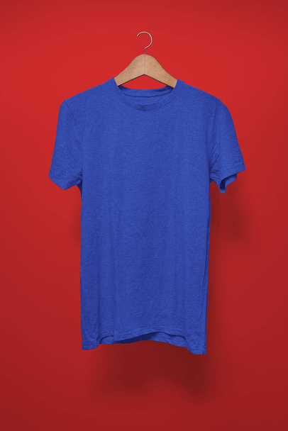 Σκούρο μπλε T-shirt σε μια κρεμάστρα σε ένα κόκκινο φόντο - Φωτογραφία, εικόνα