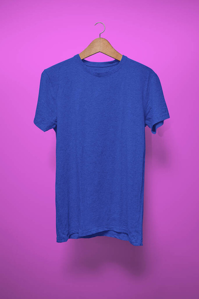 紫色の背景をしたハンガーにダークブルーのTシャツ - 写真・画像