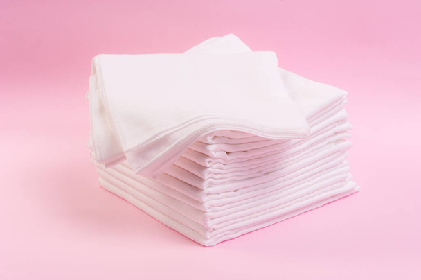 Pañales de tela de bebé blancos y suaves de primer plano sobre fondo rosa
 - Foto, imagen