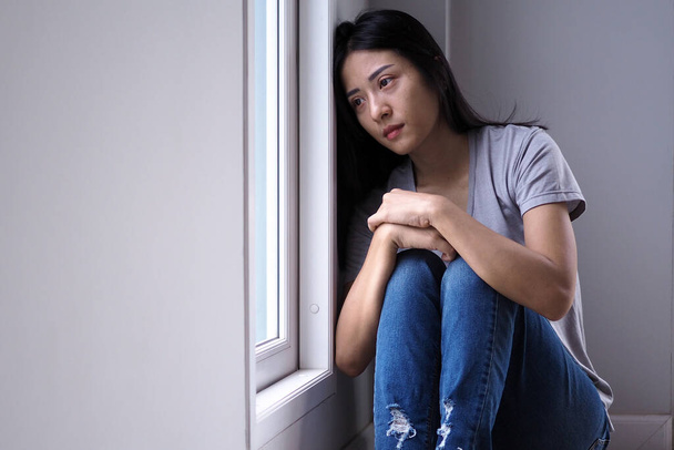 Asiatisches Mädchen sitzt allein im Haus. Depressionskonzept - Foto, Bild
