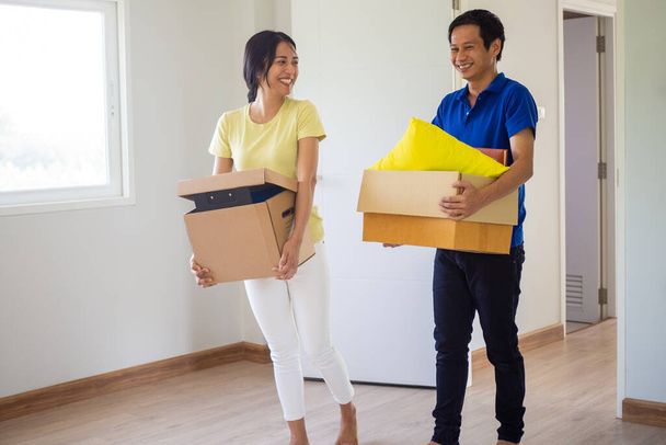 Ευτυχισμένα ζευγάρια κρατούν χάρτινα κουτιά που κρατούν προσωπικά αντικείμενα και μεταφέρουν αντικείμενα στο νέο τους σπίτι. - Φωτογραφία, εικόνα