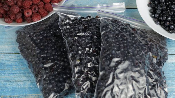 Pakowanie jagód w plastikowe torby na suwak do zamrożenia. Zamrożone owoce konserwujące, owoce jagodowe - Zdjęcie, obraz